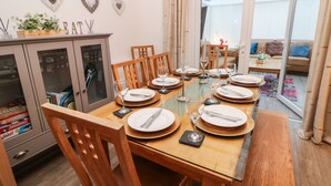 Un coin repas avec une table à plateau de verre, dressée pour six personnes, entourée de chaises en bois.