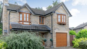 Une maison en pierre avec un grand garage, une véranda et un jardin bien entretenu.