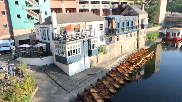 A riverside building with a dock of wooden boats.