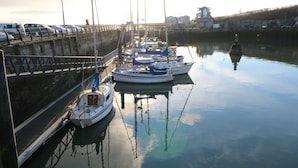 A marina with several boats docked, a bridge, and a building in the background.