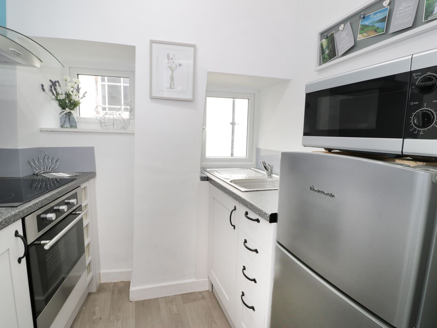 A modern kitchen with stainless steel appliances, white cabinetry, and a window providing natural light.