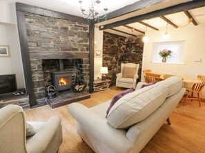 Ein gemütliches Wohnzimmer mit Kamin aus Stein, einer bequemen Couch, einem Essbereich mit Holzmöbeln und einer Steinwand.