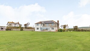 A two-story house with a large front lawn and a conservatory. - Penhallick House (Tintagel)