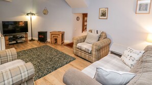 A cozy living room with a flat-screen TV, a fireplace, and a plaid sofa. - Bramla (Saltburn-by-the-Sea)