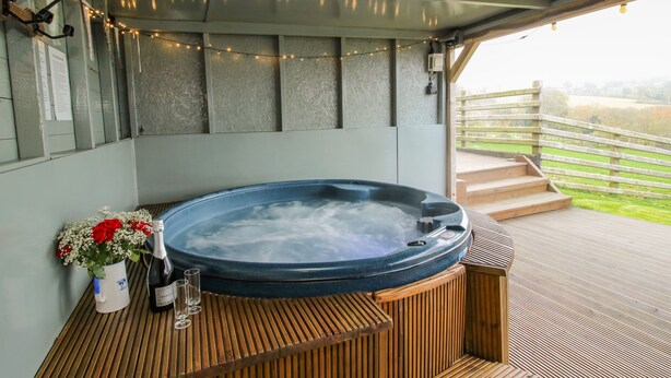 A hot tub with a wooden deck, string lights, and a wooden fence overlooking a grassy area. - Shepherds Cabin at Titterstone Hot Tub &amp; Dog-friendly Near Ludlow (Ludlow)