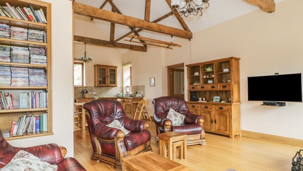 Ein geräumiges Wohnzimmer mit Ledersofas, einem Holztisch und einem Bücherregal voller Bücher.