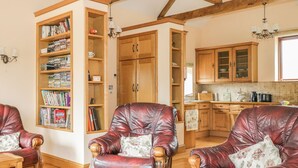 Ein gemütliches Wohnzimmer mit zwei Ledersesseln, einem Holztisch und einem Bücherregal voller Bücher.