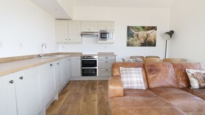 Eine moderne Küche mit weißen Schränken, Edelstahlgeräten und einer Holzausziehtafel.