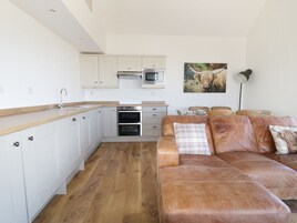 Una cocina moderna con gabinetes blancos, electrodomésticos de acero inoxidable y encimera de madera.