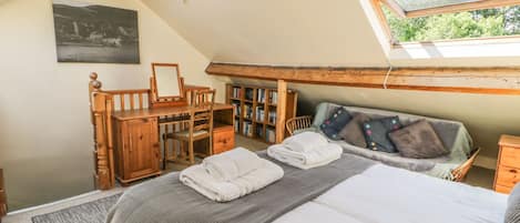 A cozy attic bedroom with a loft bed, a desk, and a bookshelf.