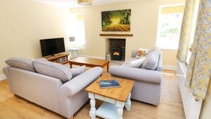 A living room with two grey sofas, a wooden coffee table, a fireplace, and a television. - Ty Ffarm at Gellilwch (Pontypridd)