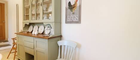 Uma cozinha com armário verde, cadeira branca e um letreiro com a inscrição 'Fresh Eggs'.