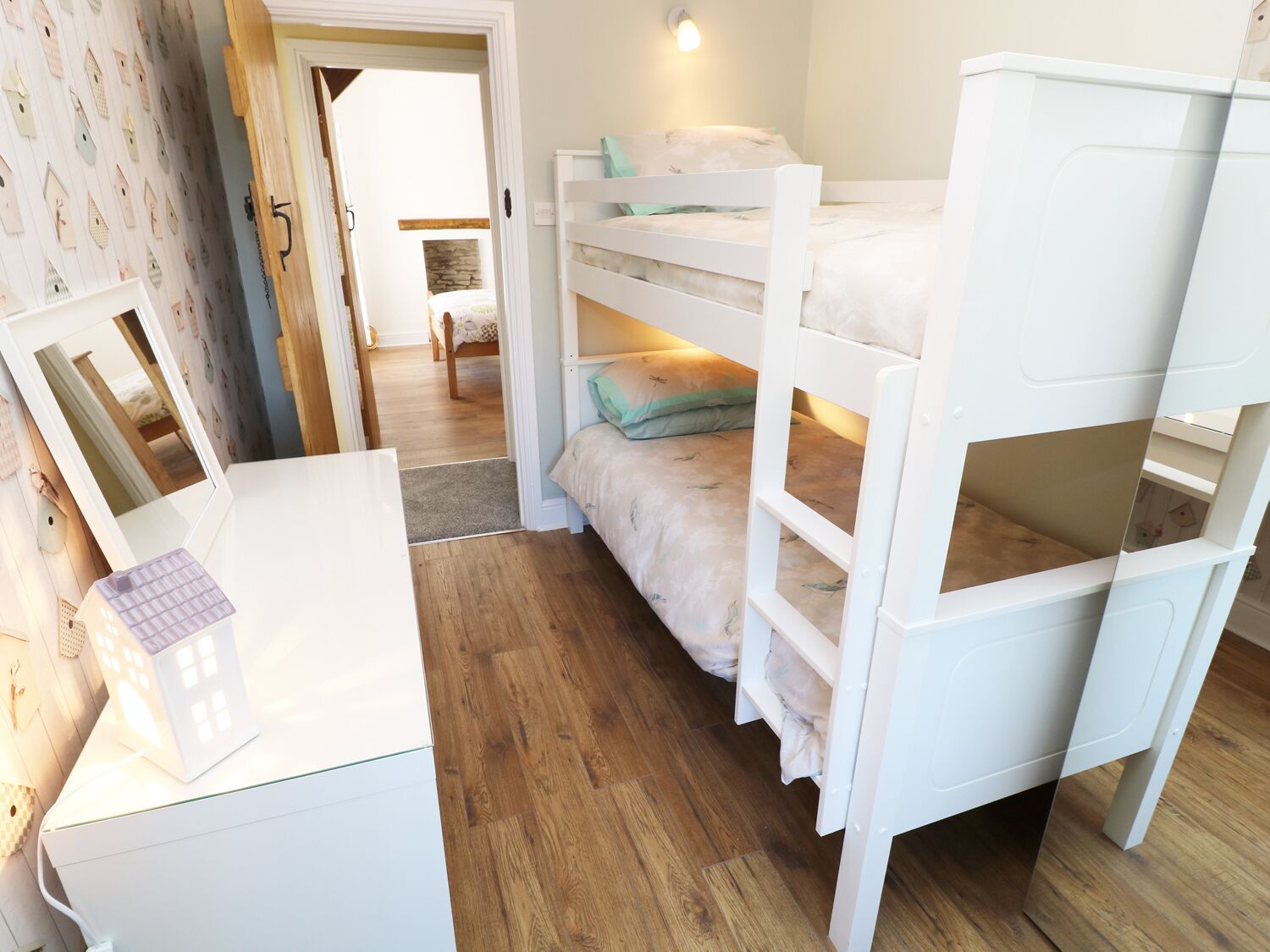 A bunk bed room with a desk and a small lamp.