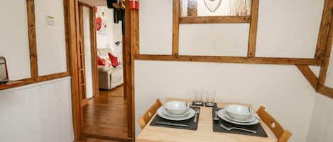 A dining area with a wooden table set for two, a fire extinguisher, and a hanging light fixture.