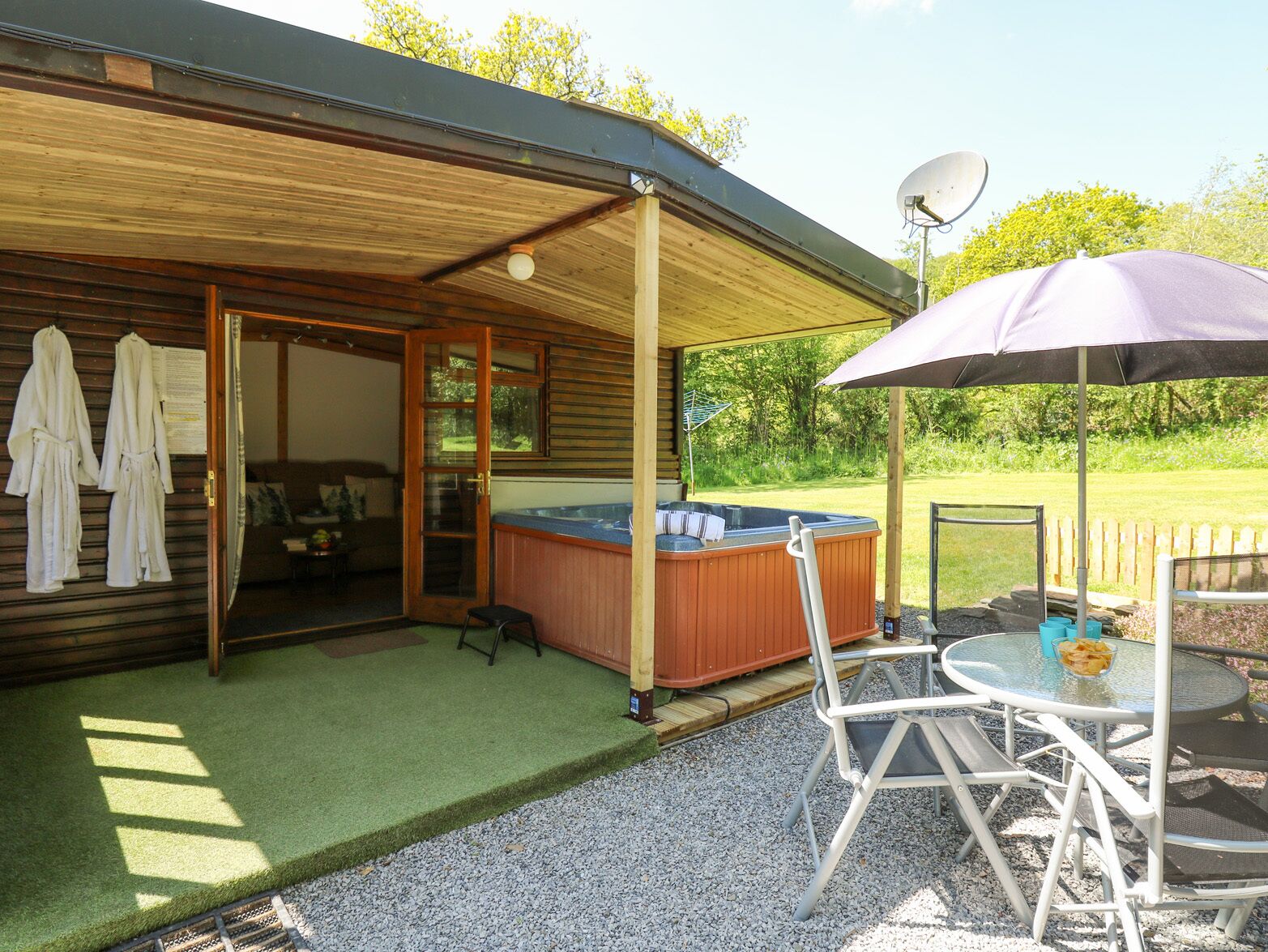 A covered outdoor area with a hot tub, a table with chairs, and a satellite dish.