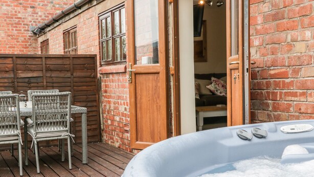 A wooden deck with wicker chairs and a hot tub. - Old Hall Barn 1 (Church Stretton)