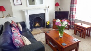 Una sala de estar con chimenea, un sofá, una mesa de centro y un televisor.