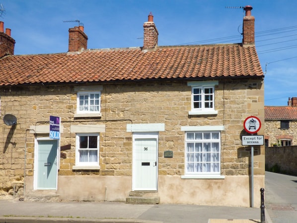 A stone building with a tiled roof, a 'SOLD' sign, and a 'No Motorcycles Except for Access' sign.