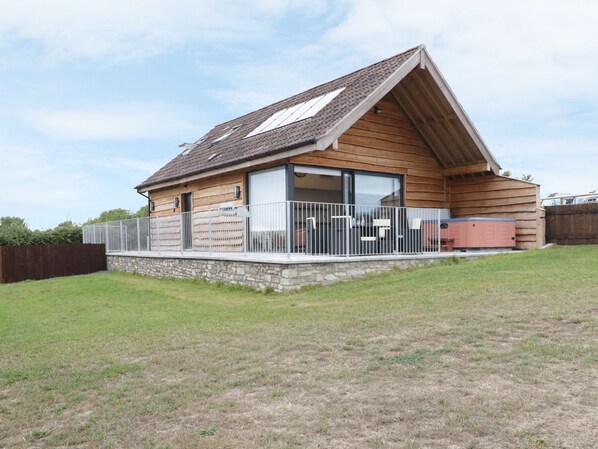 A wooden cabin with a sloped roof, large windows, and a stone foundation.