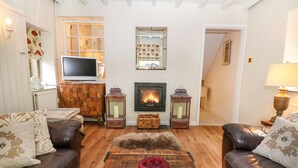 Una sala de estar acogedora con sofás de cuero, una mesa de centro de madera, una chimenea y un televisor.