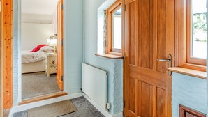 A room with a wooden door, a window, and a radiator. - Foxlair Cottage (Minehead)