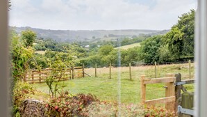 A rural landscape with rolling hills, a wooden fence, and a stone wall. - Foxlair Cottage (Minehead)