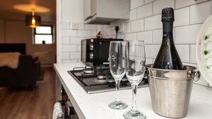 A modern kitchen with white tiles, a stainless steel sink, and a bottle of wine in a bucket. - 2 Ysgoldy (Bangor)