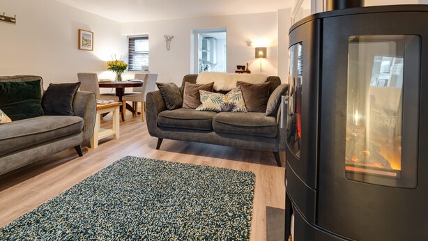 A modern living room with a sofa, a dining table, and a fireplace. - 2 Ysgoldy (Bangor)