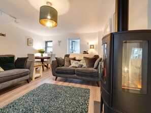 A modern living room with a sofa, a dining table, and a fireplace. - 2 Ysgoldy (Bangor)