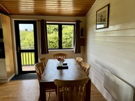 Un comedor con mesa y sillas de madera, una ventana con cortinas, y un cuadro enmarcado en la pared.
