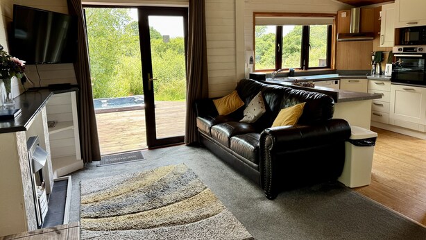 Een moderne woonkamer met een leren bank, een flatscreen televisie en een grote schuifglazen deur die uitkomt op een balkon.