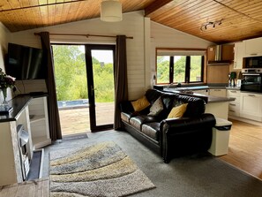 Moderni olohuone, jossa on nahkasohva, litteänäyttöinen televisio ja suuri liukuovi, joka johtaa parvekkeelle.