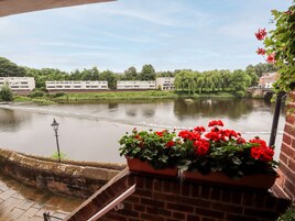 A riverside view with a brick wall and potted red flowers.