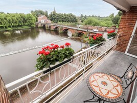 A balcony with a view of a river, a bridge, and a church spire.