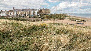 A coastal building with multiple stories, a sandy beach in the background, and a grassy foreground. - Larksbay View (Redcar)