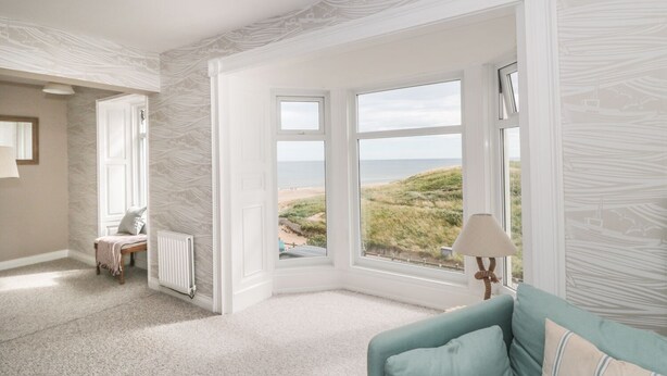A room with a view of the beach, a window with a view, a radiator, a bench, and a lamp. - Larksbay View (Redcar)