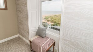 A corner room with a view of the beach, a bench, and patterned wallpaper. - Larksbay View (Redcar)