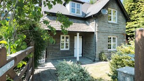 Une maison en pierre avec un toit en pente, une porte blanche et une antenne parabolique.