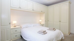 Une chambre à coucher avec un grand lit, deux tables de chevet et une armoire.