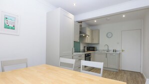 Une cuisine de taille réduite avec des meubles blancs, un four à micro-ondes et une horloge au mur.