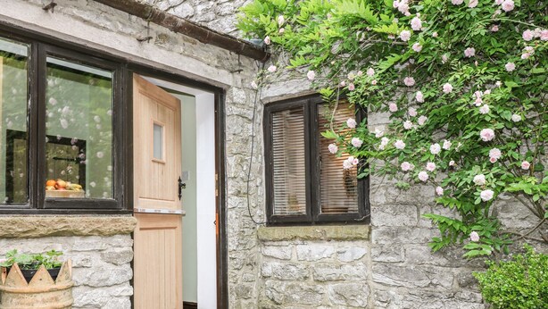 Un edificio de piedra con puerta de madera y una ventana con contraventanas.
