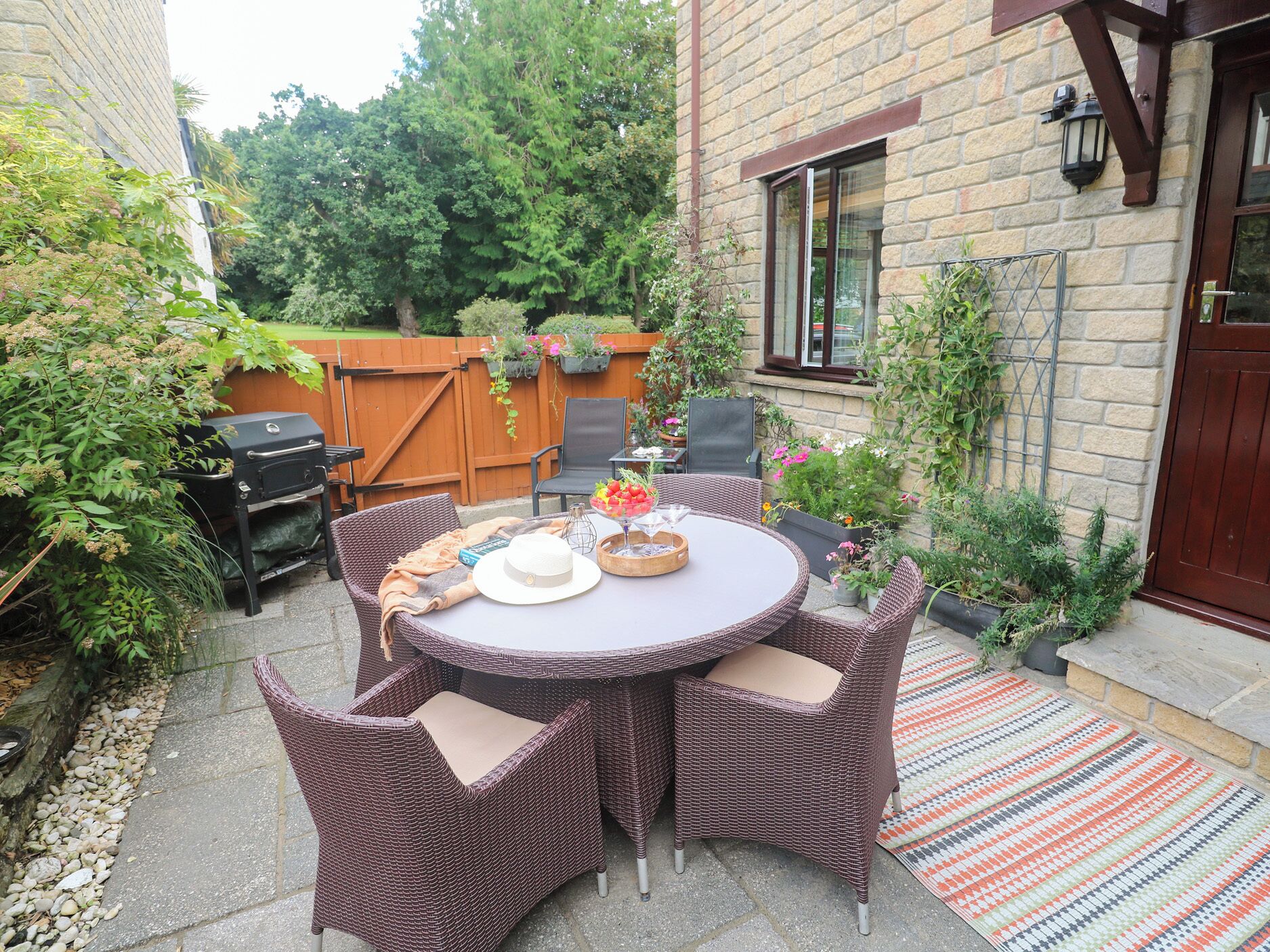 A patio with wicker furniture, a round table, and a barbecue grill.