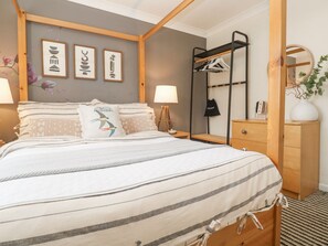Une chambre à coucher comprenant un lit, des tables de chevet, une commode, un miroir et des œuvres d’art murales.