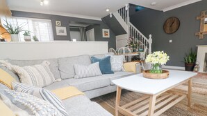 Un salon avec un canapé gris, une table basse blanche et un escalier menant à l’étage supérieur.