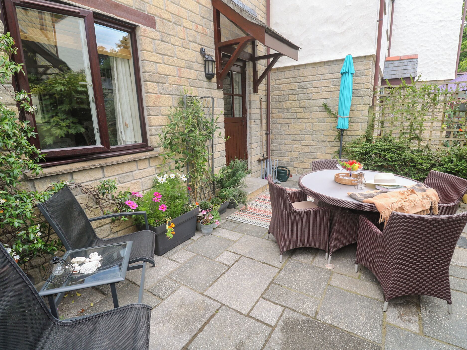 Eine Terrasse mit Korbmöbeln, einem Tisch mit Obstschale und Topfpflanzen.