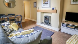 A living room with a sofa, chairs, a fireplace, a television, and a bookshelf. - The Garden Flat (Harrogate)