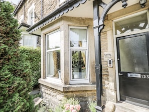 A corner building with a stone facade, a black door labeled "Edina Ville," and a window with a white frame. - The Garden Flat (Harrogate)
