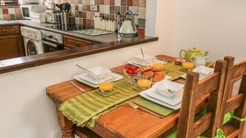 Un desayuno preparado con una mesa para dos personas, incluyendo platos, vasos y un bol de fresas.