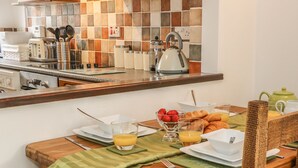 Un esmorzar preparat amb una taula de fusta, plats, gots i diferents aliments per esmorzar, com ara croissants i fruita.