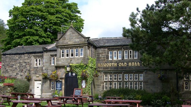 Edifici de pedra tradicional amb un rètol que diu "Haworth Old Hall".